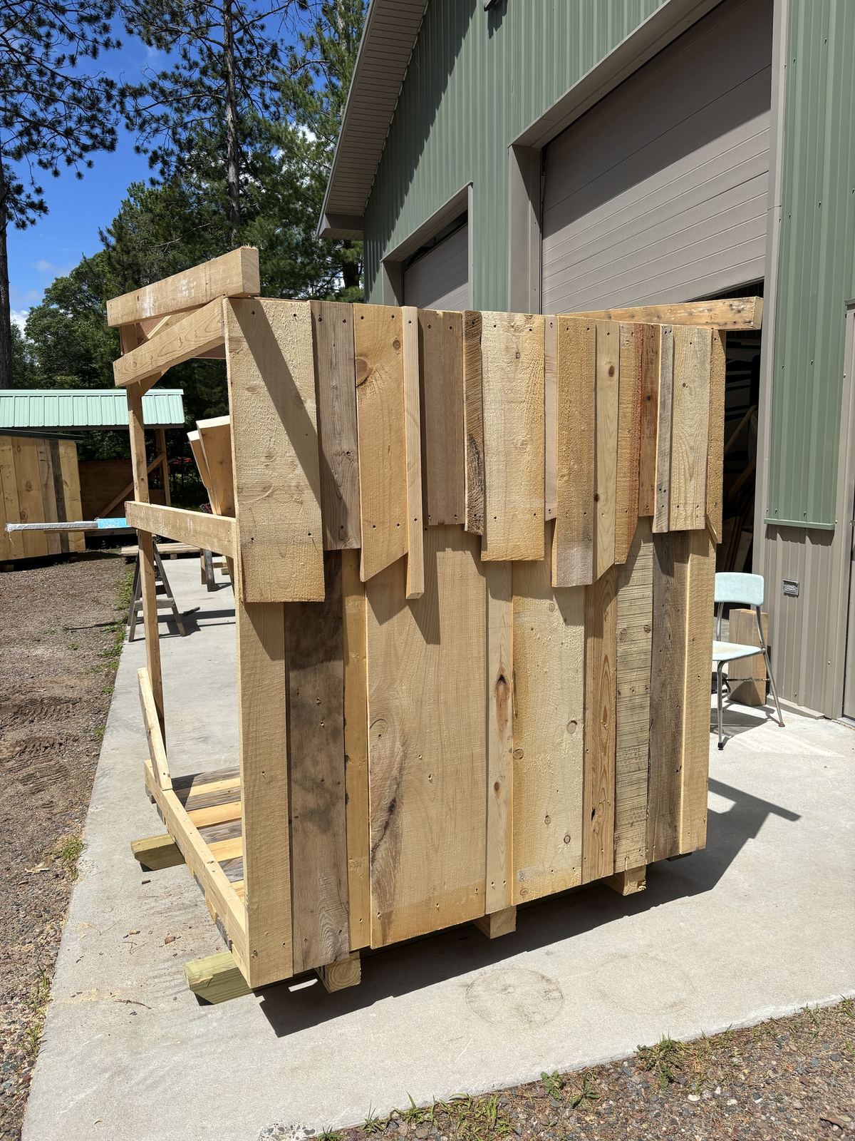 Reclaimed boards being fastened to the back of a shed